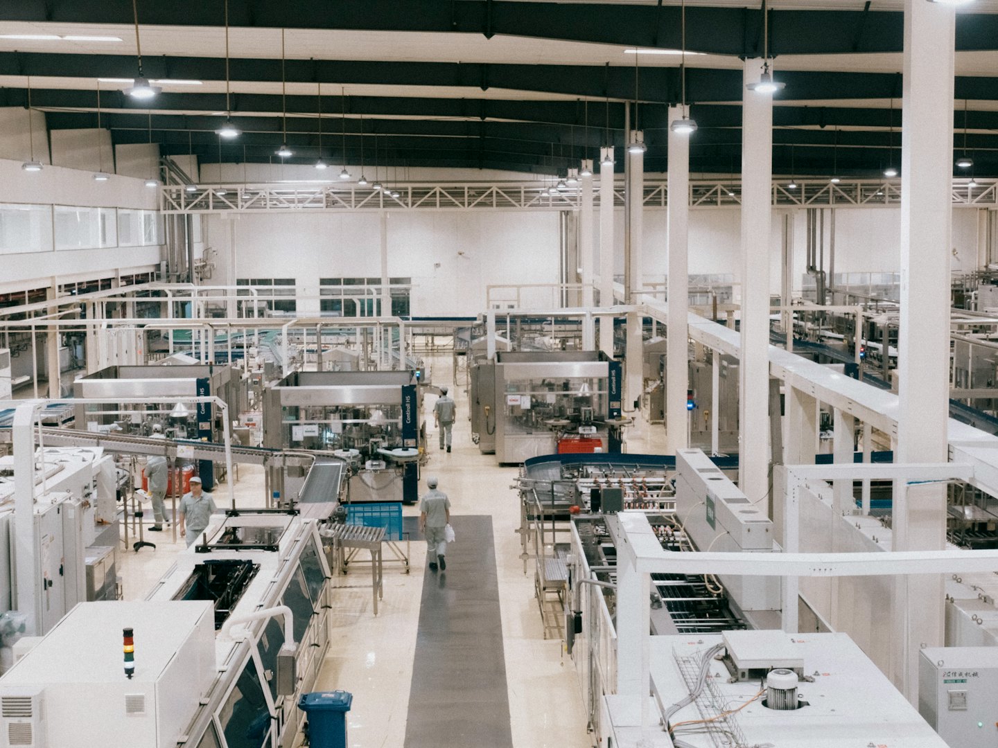 Trabajadores moviéndose entre maquinaria automatizada en una línea de producción.